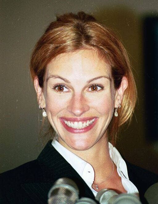 Julia Roberts smiling broadly, hair pinned up, in a dark jacket