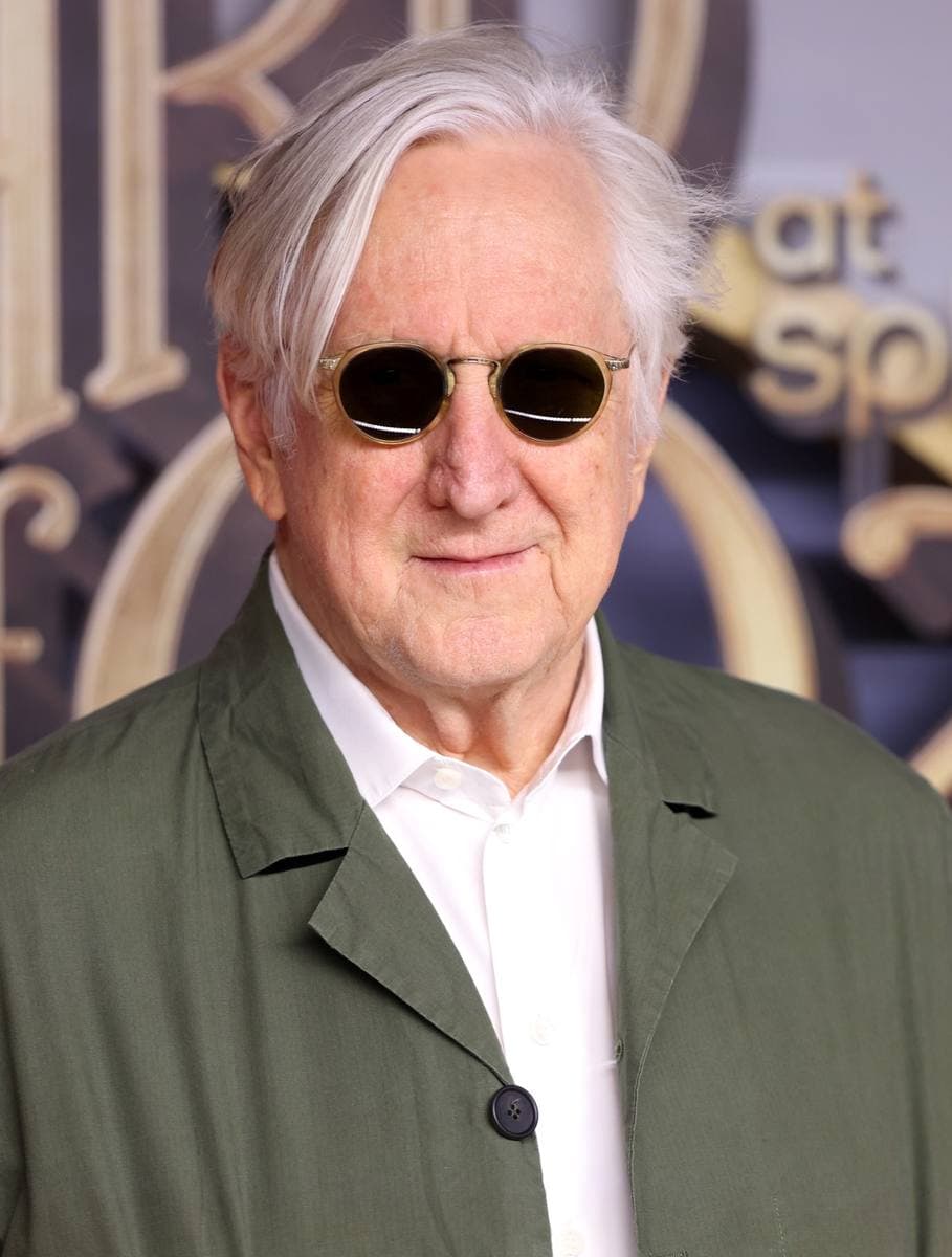 T Bone Burnett with white hair and round dark glasses, in a sage jacket