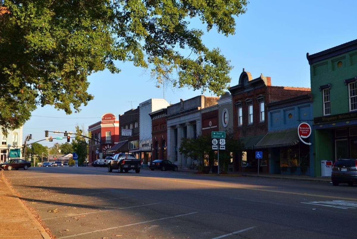 A row of nineteenth-century brick shopfronts along an empty street under a blue sky