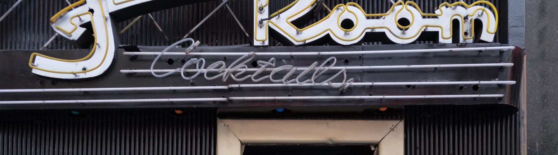 The Frolic Room sign and Cocktails lettering in neon above a dark doorway