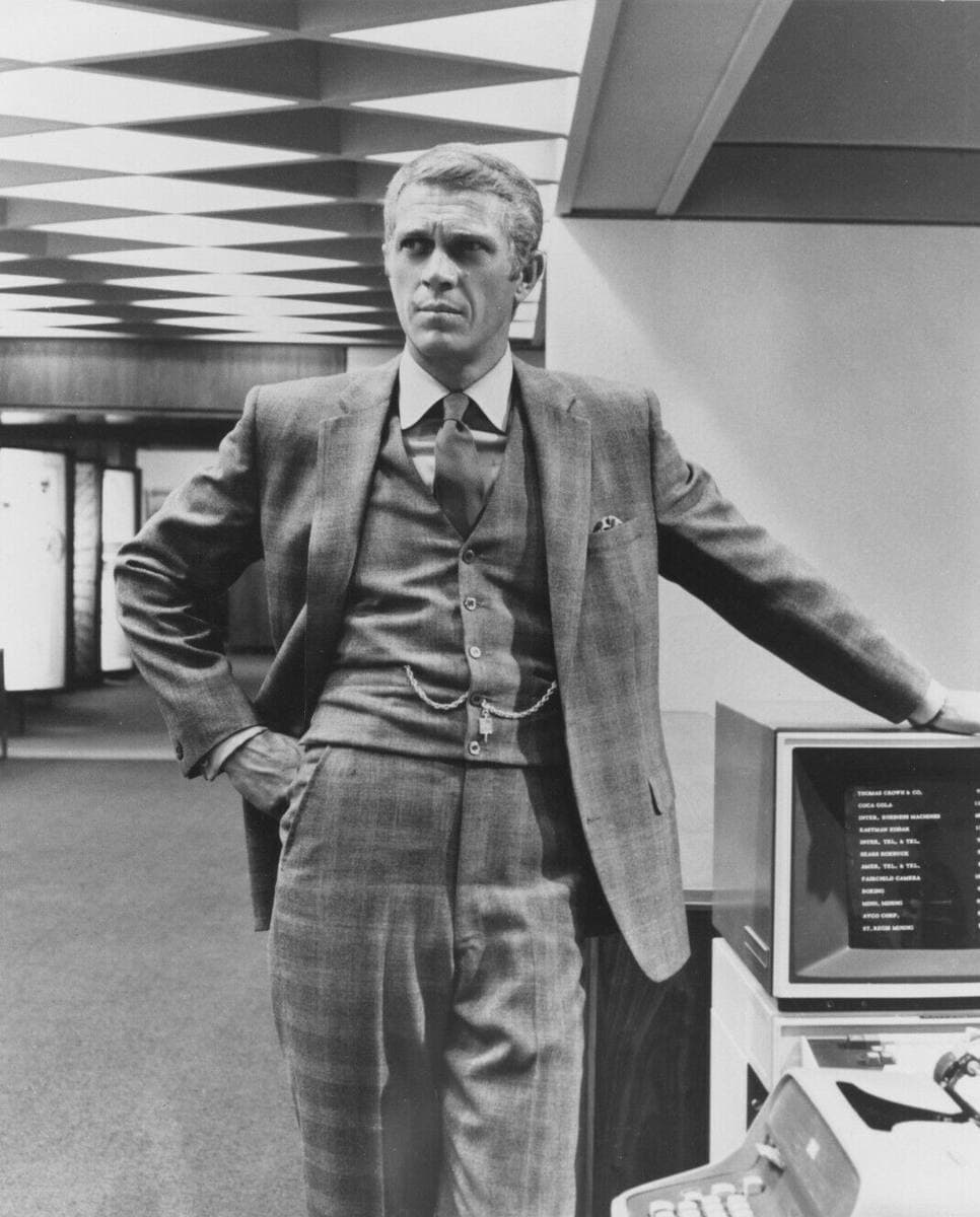 Black-and-white photo of Steve McQueen in a three-piece check suit, hand on hip