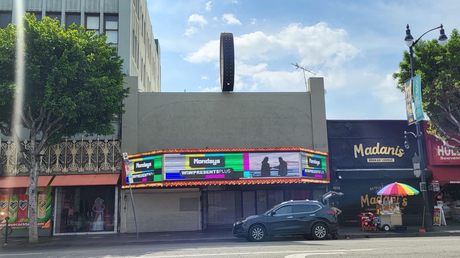 A low theatre front with a lit marquee and a round tower above it on Hollywood Boulevard