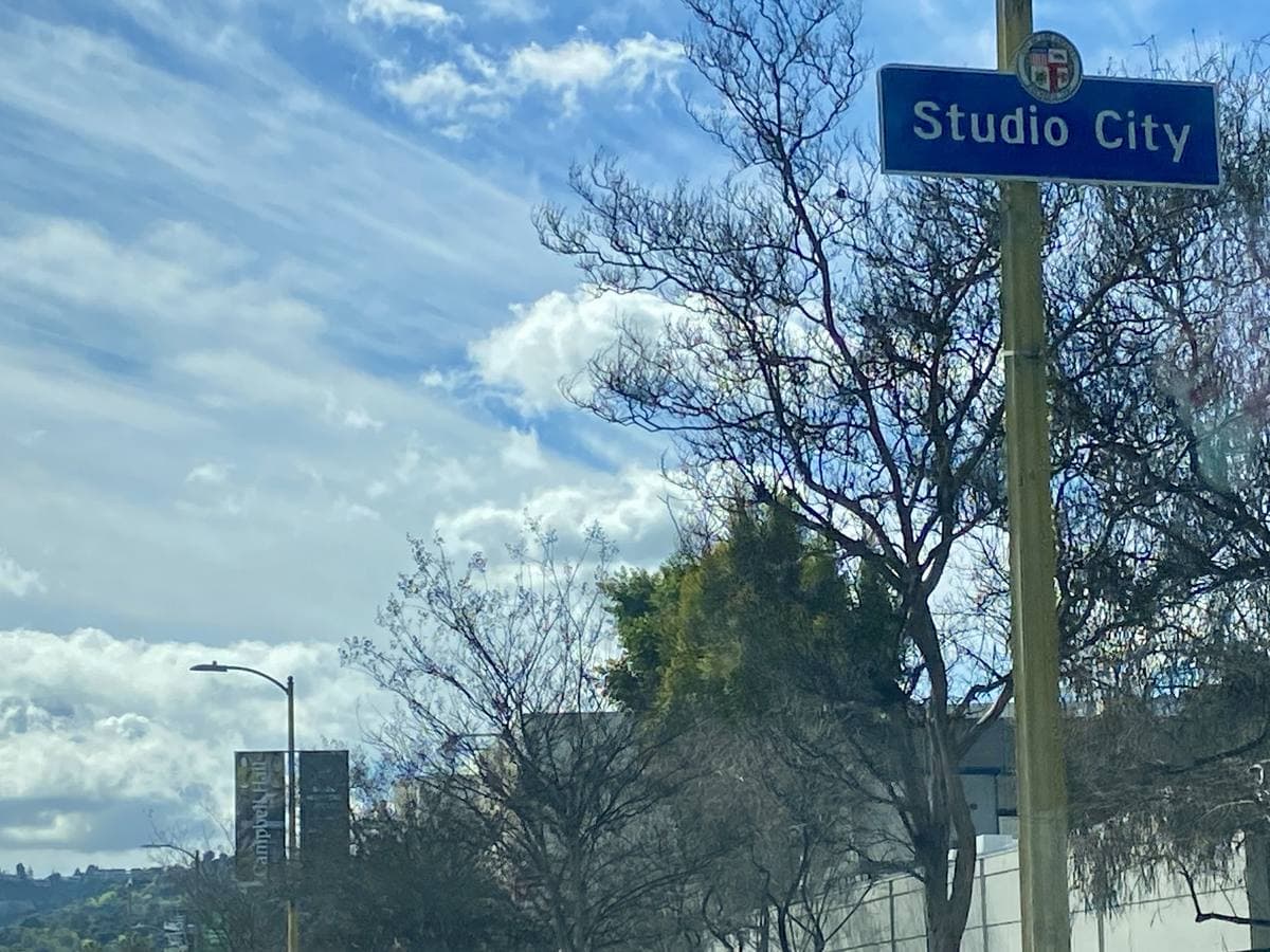 A blue Studio City sign on a pole under a cloudy sky