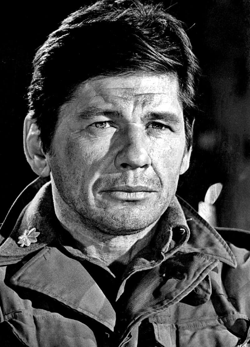 Charles Bronson, lined face and dark hair, in an army jacket, black and white