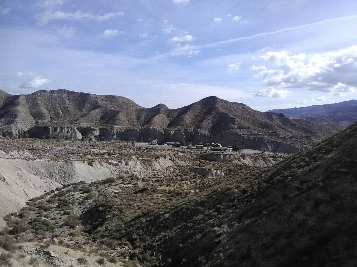 Badland hills and a dry riverbed with the western village small in the distance