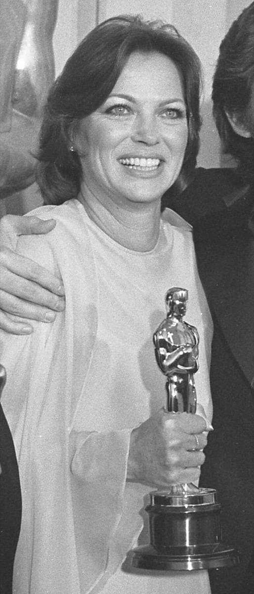 Louise Fletcher in a long pale gown holding an Oscar statuette