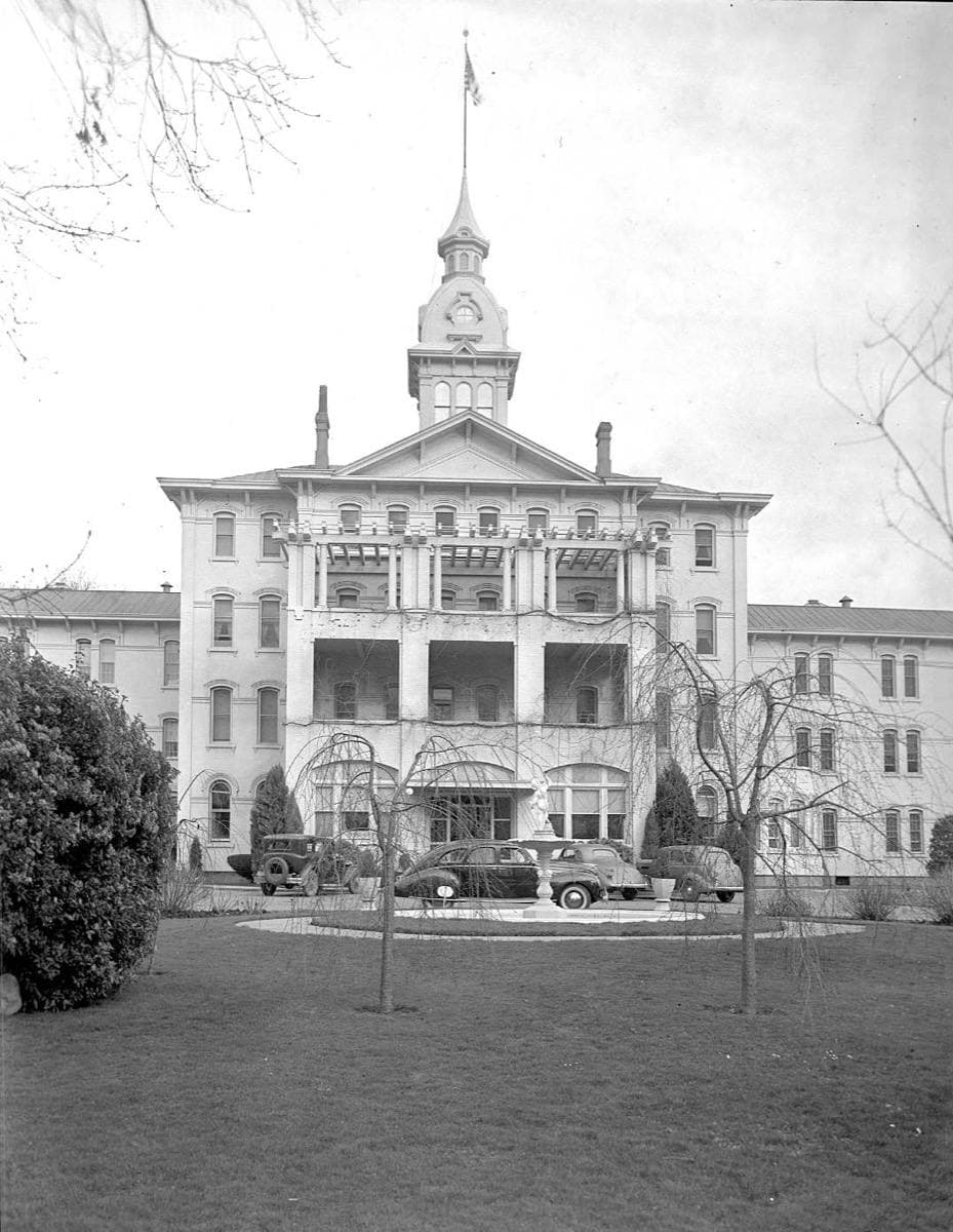 A tree-lined drive leading to the hospital's white main building, 1940