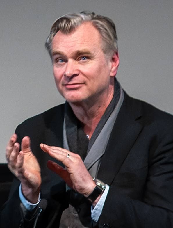 Colour photograph of a grey-haired man in a dark jacket and scarf, clapping