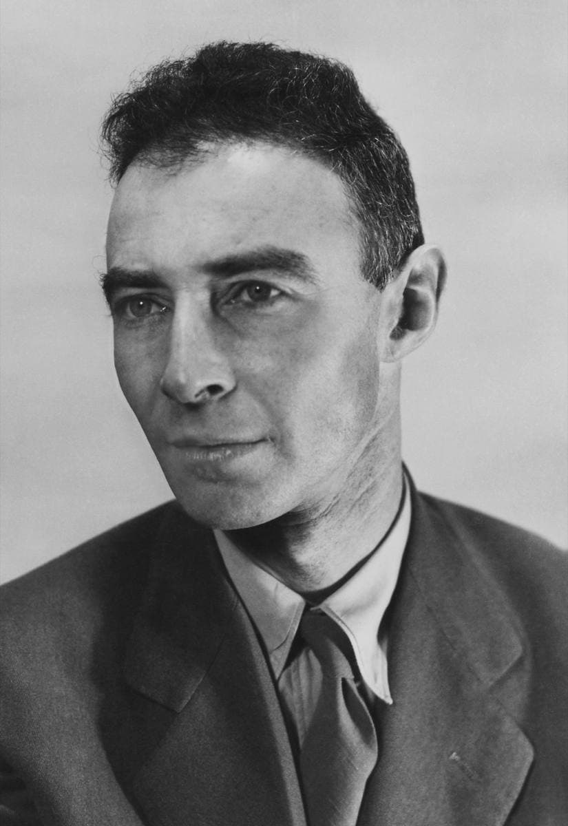A black-and-white portrait of J. Robert Oppenheimer in a jacket and tie, close-cropped hair