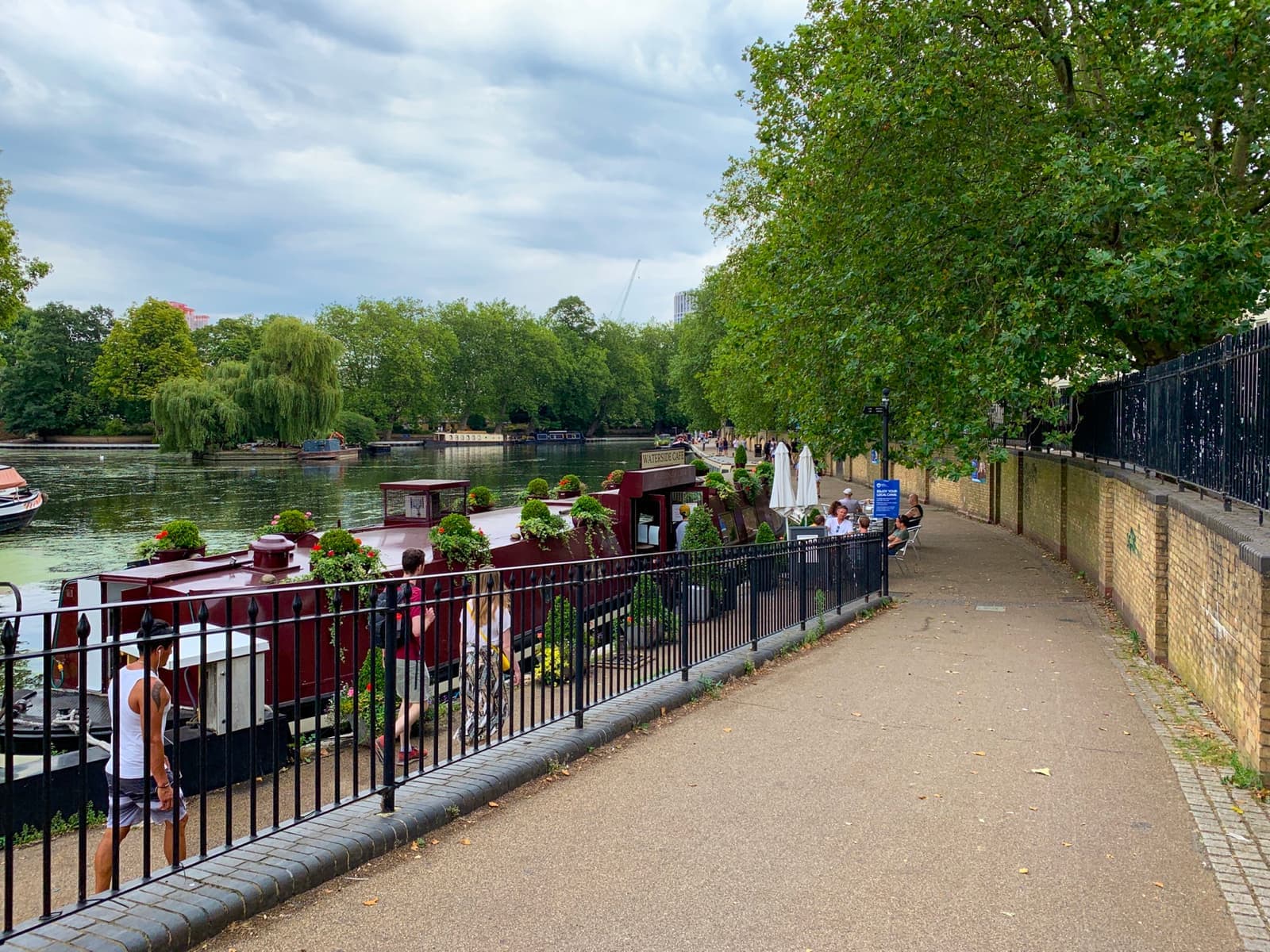 Narrowboats moored on the canal pool at Little Venice under summer trees