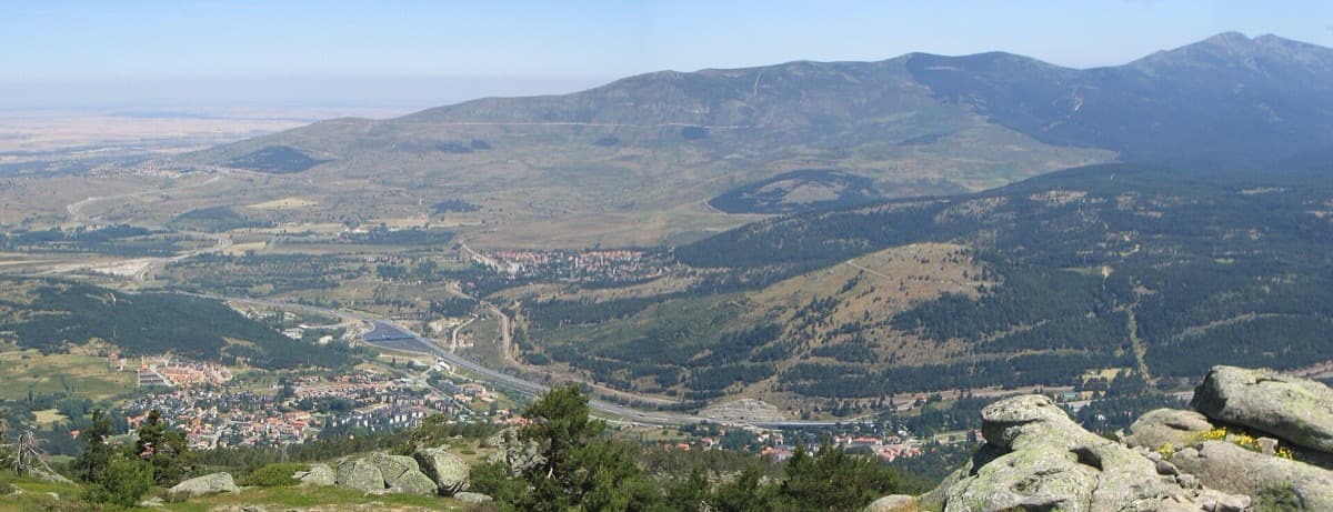 Wide view over the valley of El Espinar and San Rafael with pine hills behind
