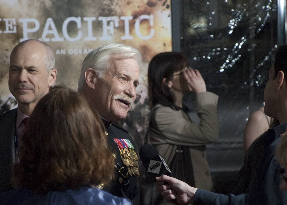 Dale Dye, white-haired, talking to reporters