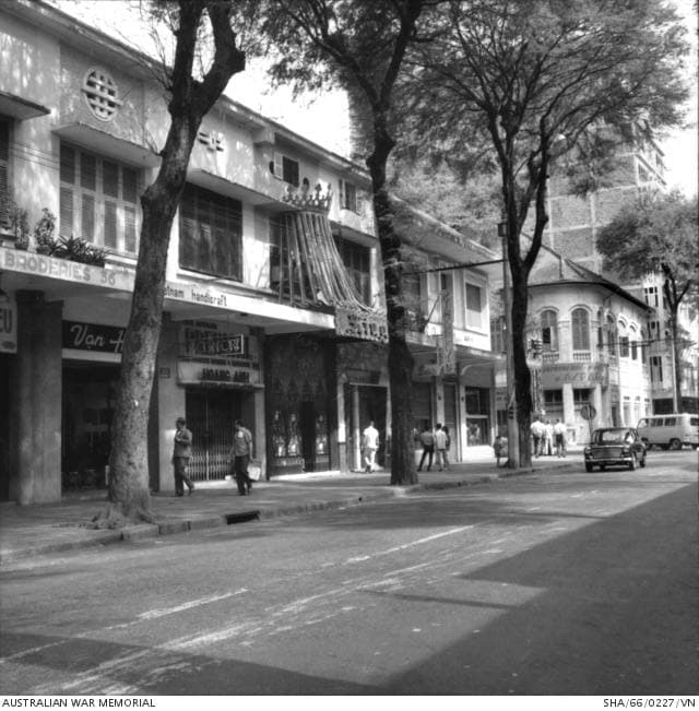 A busy street in Saigon in 1966 with shopfronts and cars