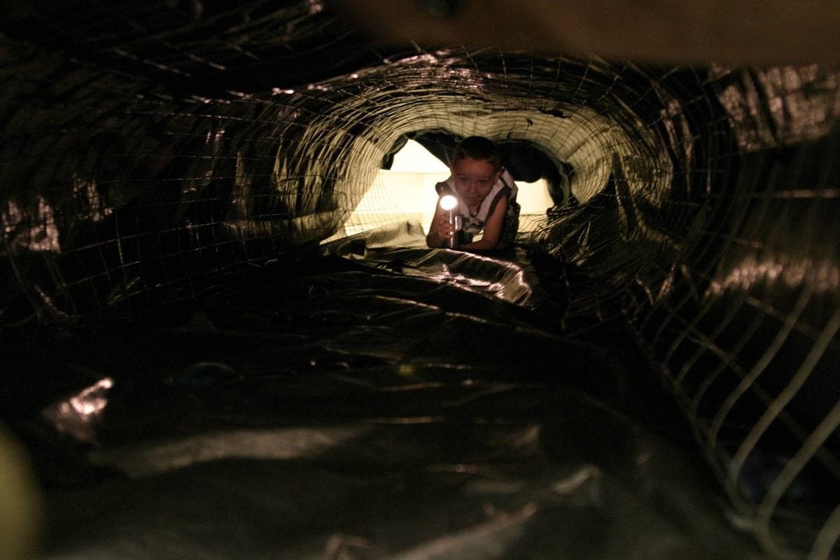 A child crawling out of a model tunnel at a museum open day