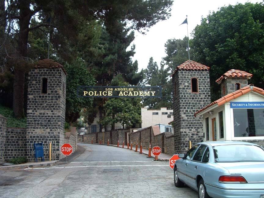 Two stone towers either side of a gated drive under a Los Angeles Police Academy sign