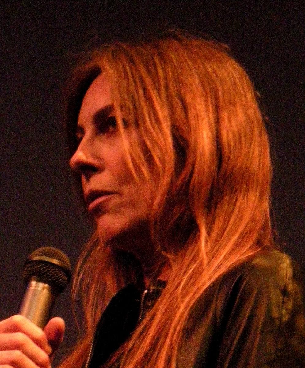 Kathryn Bigelow with long auburn hair, speaking into a microphone