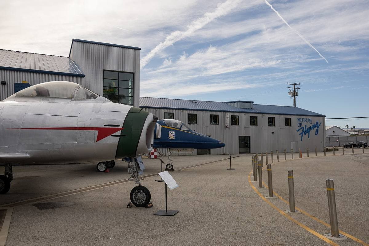 A jet on display outside a blue and grey hangar building