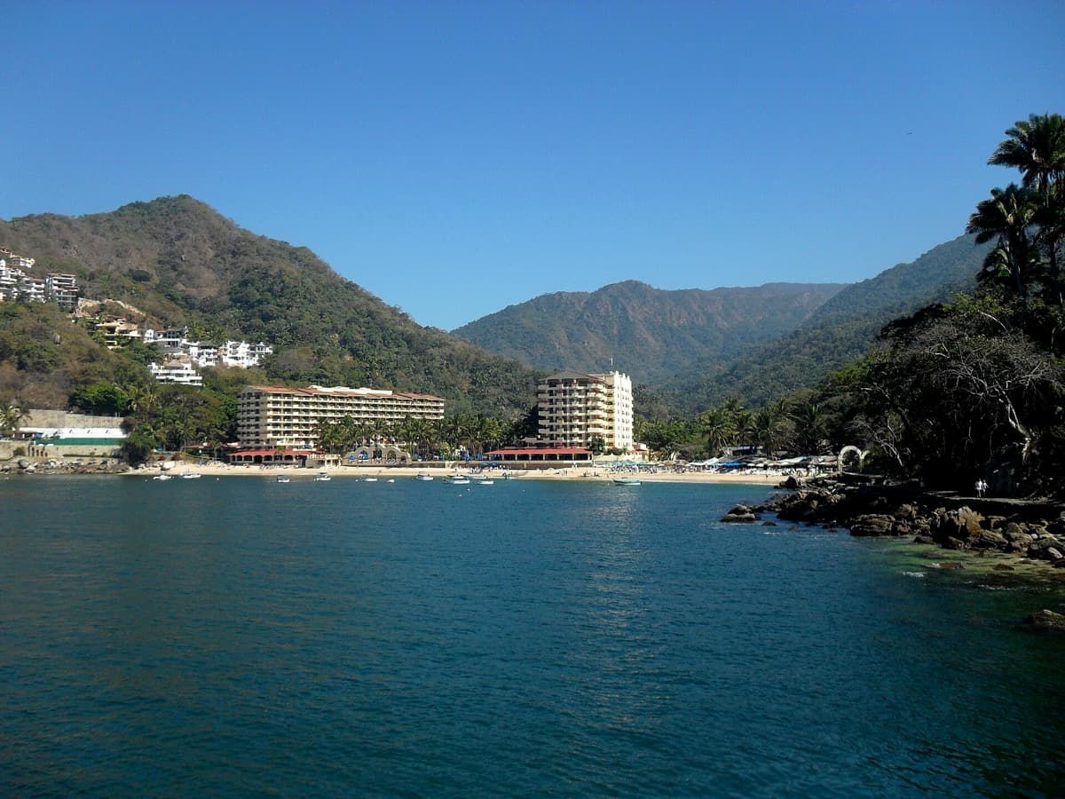 Mismaloya shoreline with palms and forested hills behind.