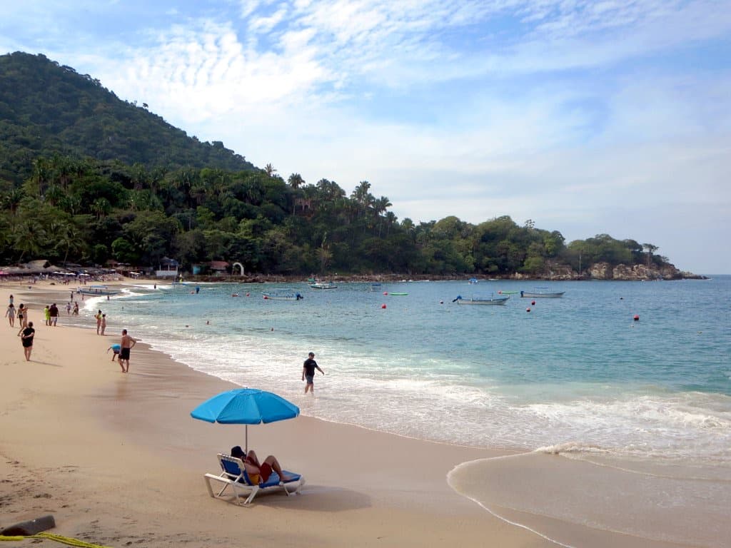 A small cove with rocks, a beach and green hills at Mismaloya.