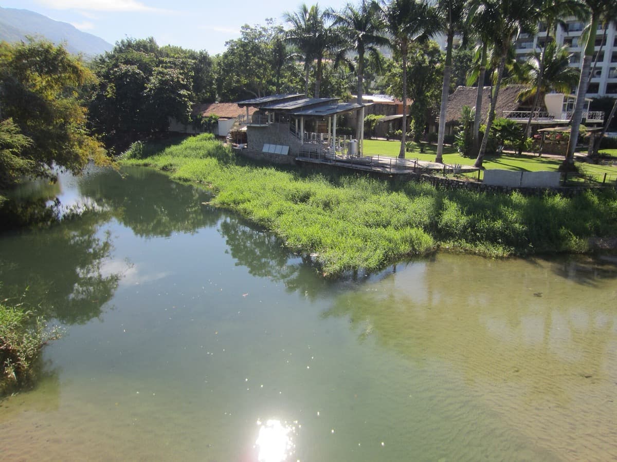 A river meeting a wide bay beside the town of Puerto Vallarta.