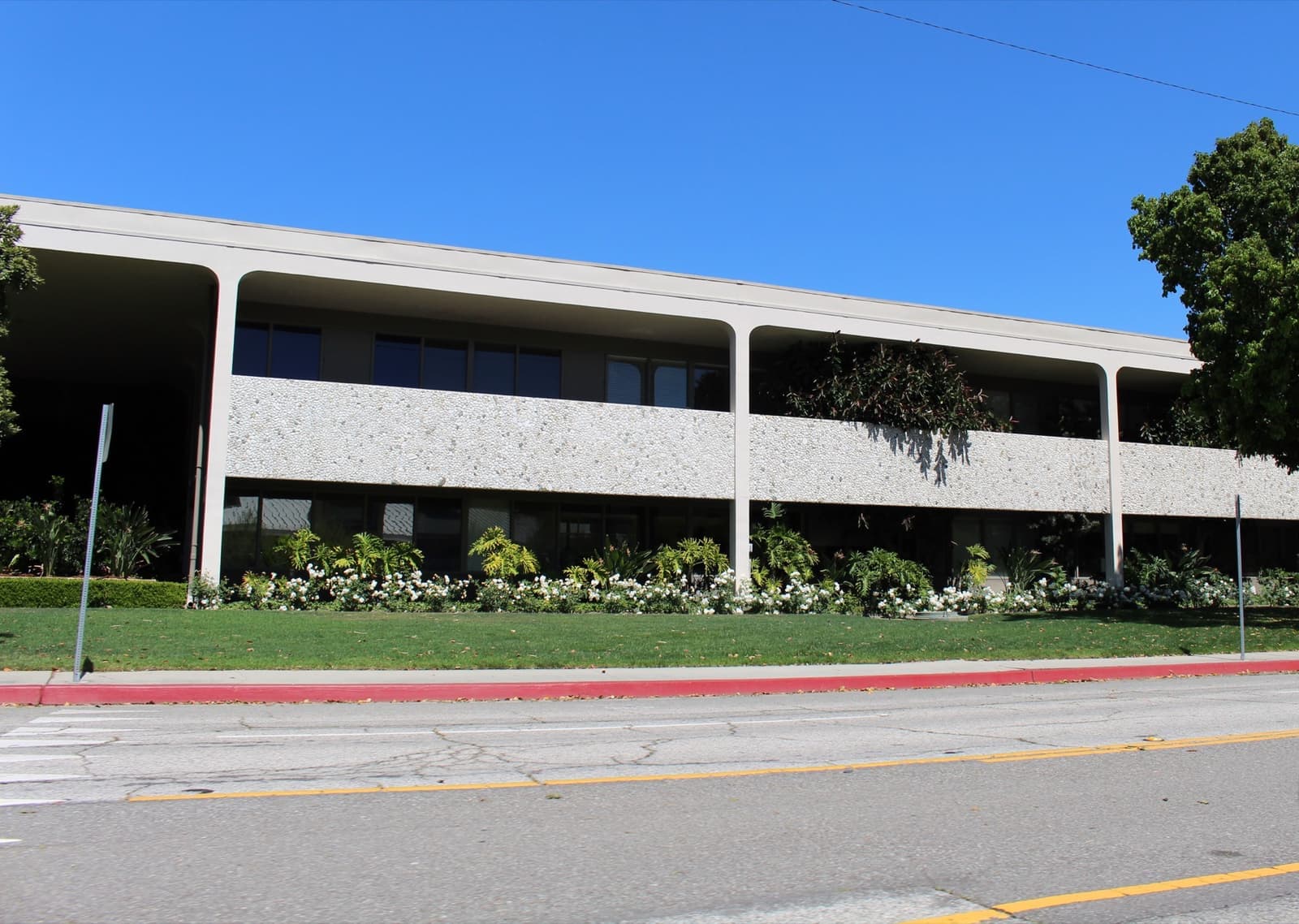 A long low mid-century office building behind a lawn