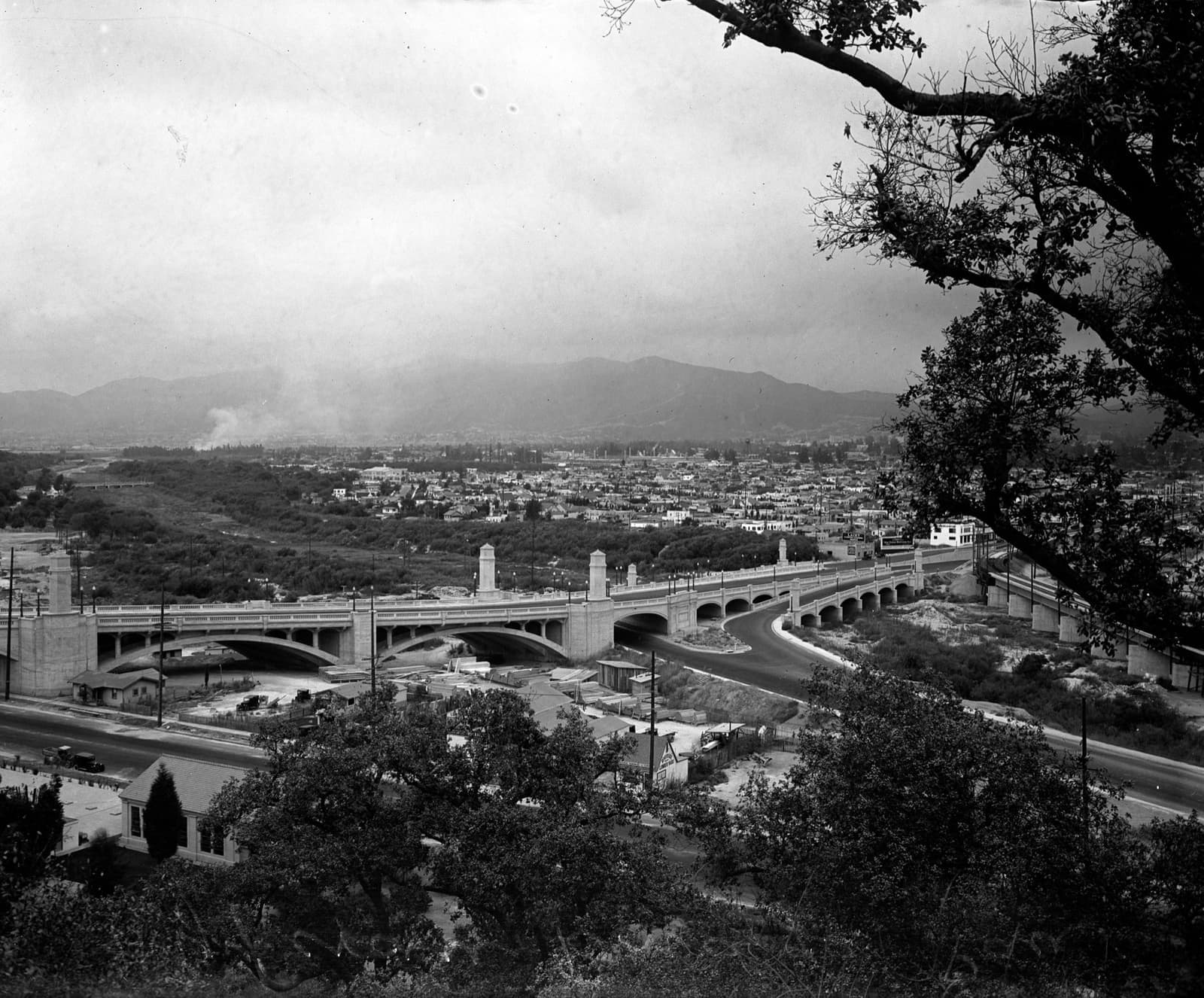 A black-and-white panorama of a long arched bridge over a river