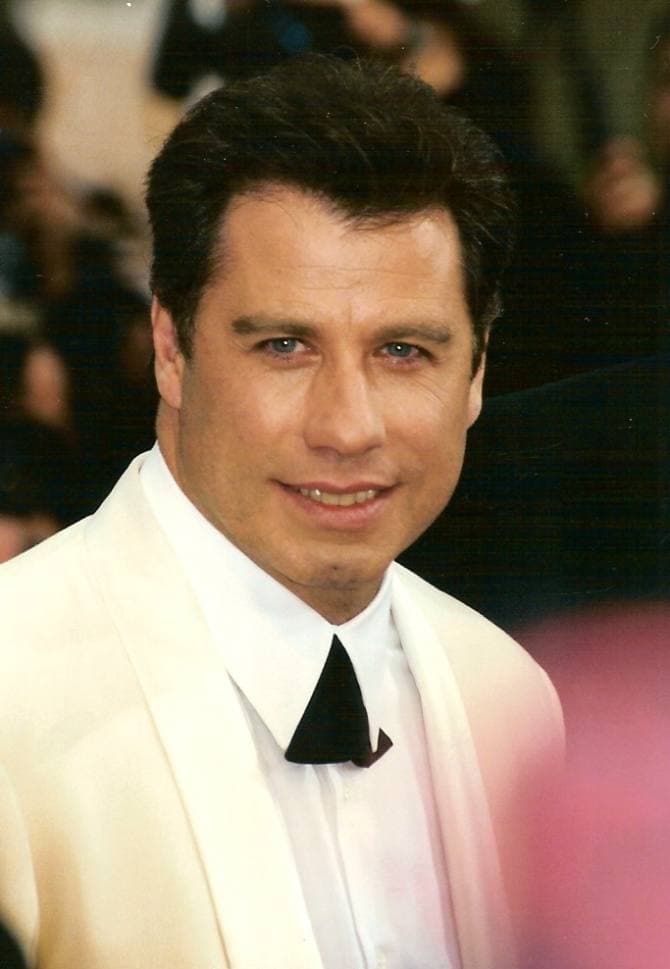 John Travolta in a white dinner jacket and black bow tie, smiling