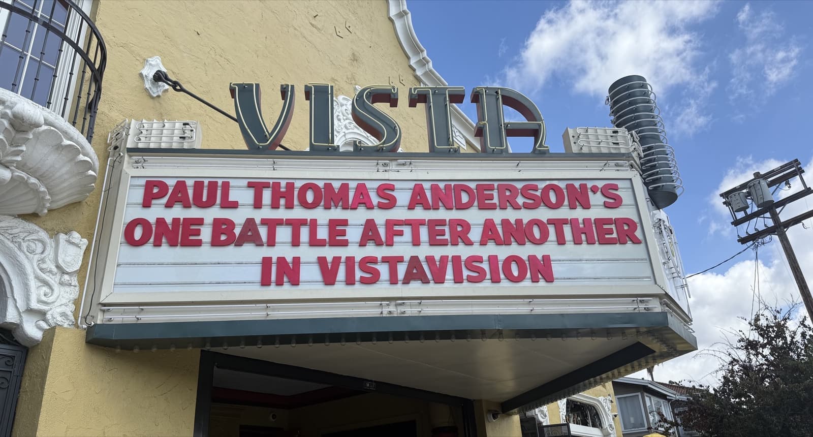 A cinema marquee with red letters under a blue sky