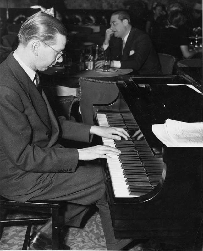 A pianist in a dinner jacket at a grand piano in a crowded 1940s nightclub