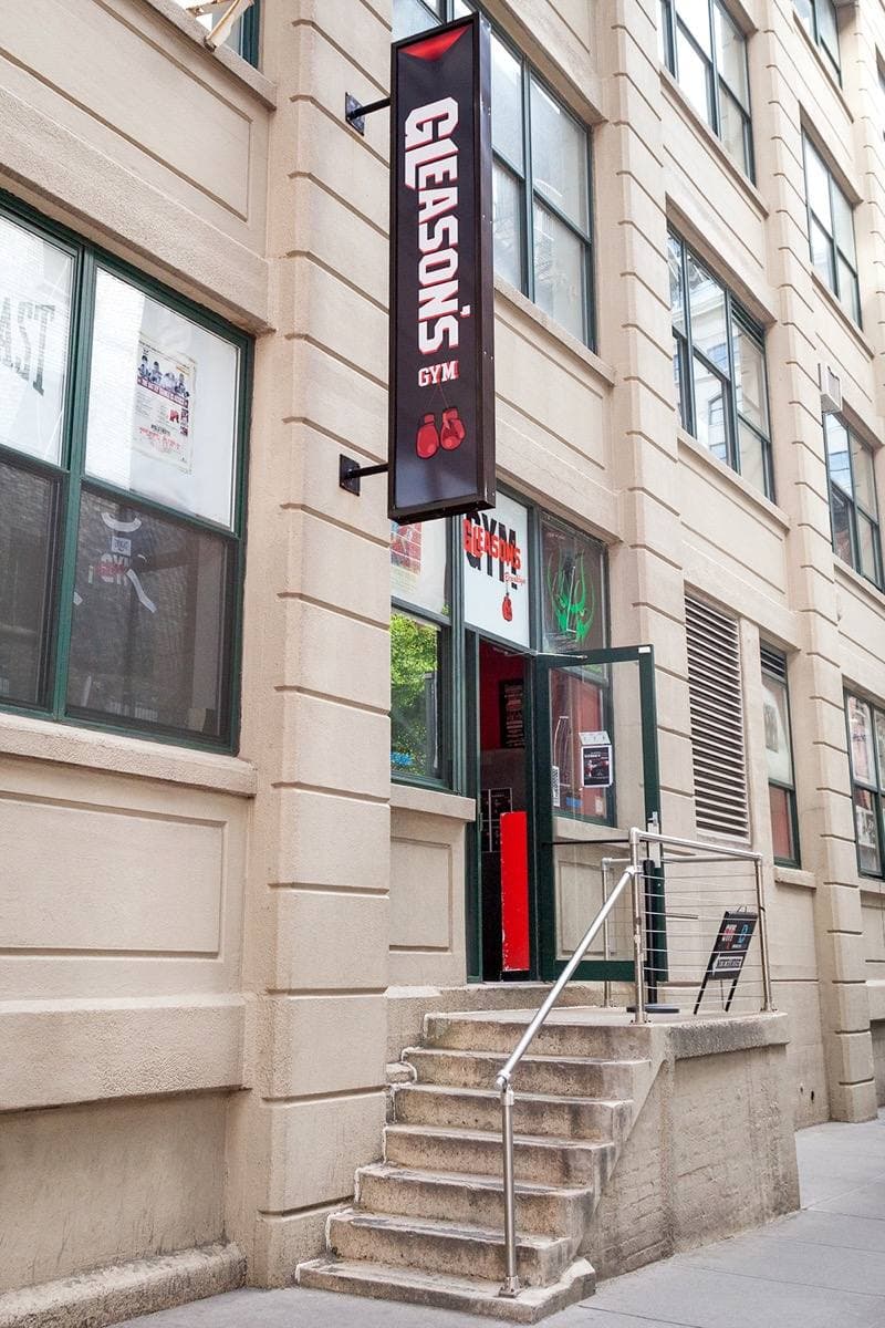 A tall sign reading Gleason’s on a building beside a doorway and steps