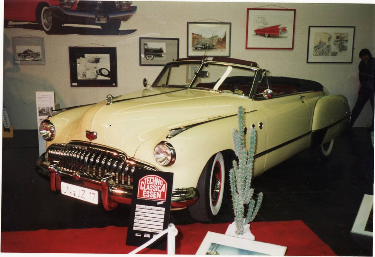 A long two-tone Buick convertible with chrome portholes on the front wing