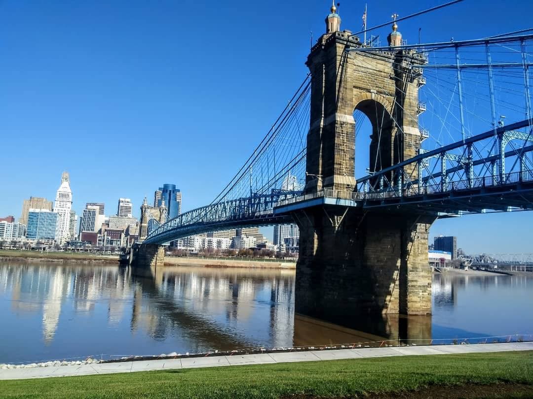 A blue suspension bridge with stone towers over a river