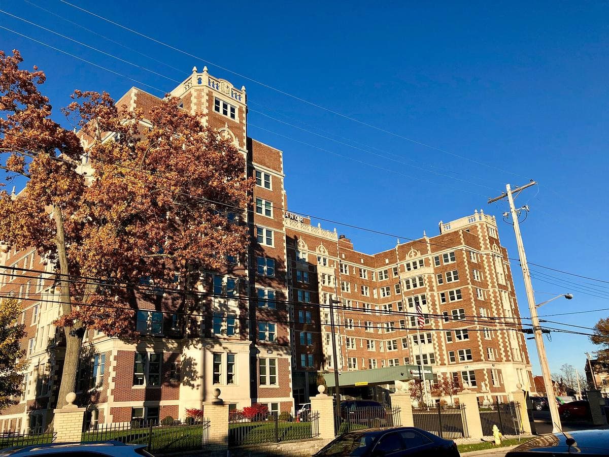 A tall brick former hotel with a columned entrance