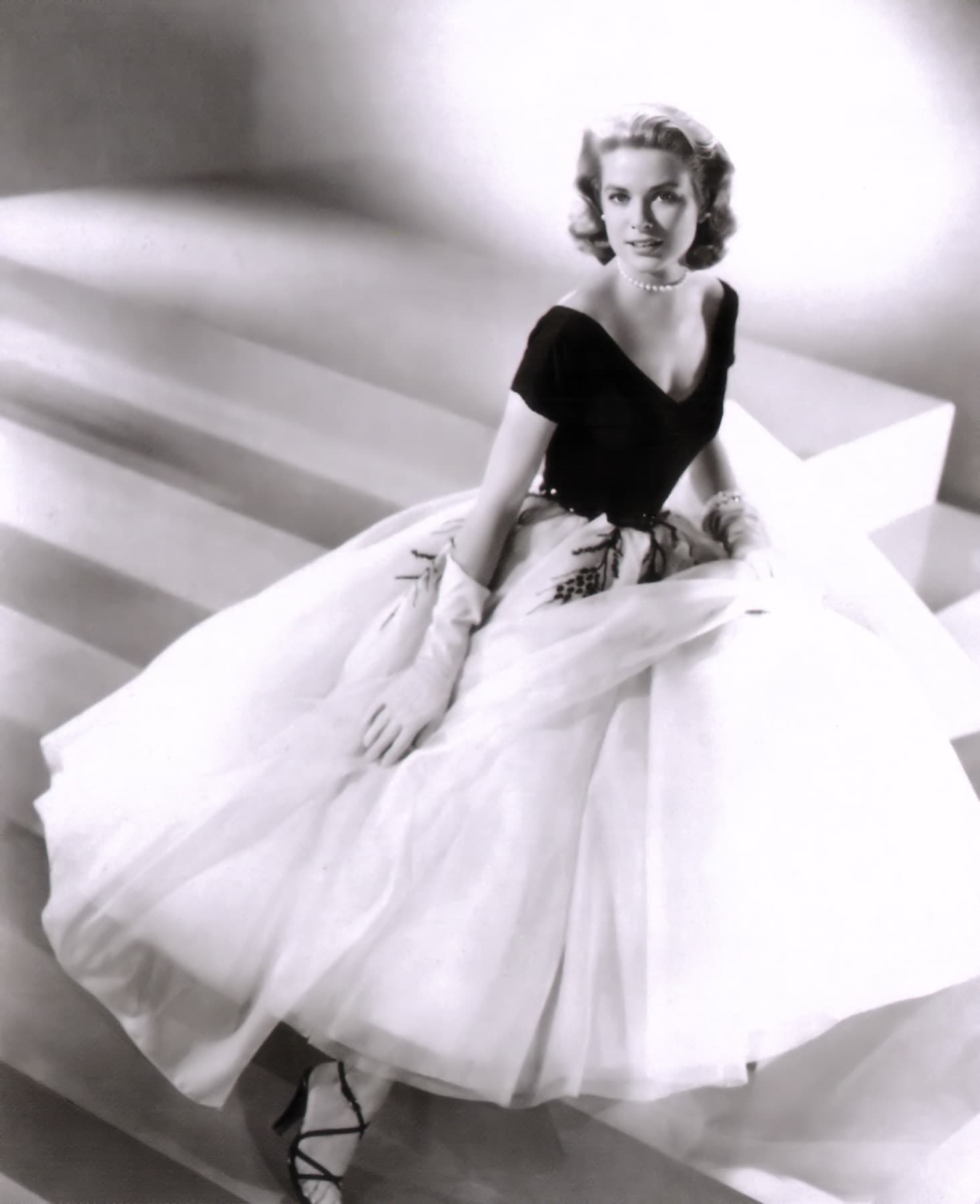 Grace Kelly seated in a full white tulle skirt and a dark fitted bodice