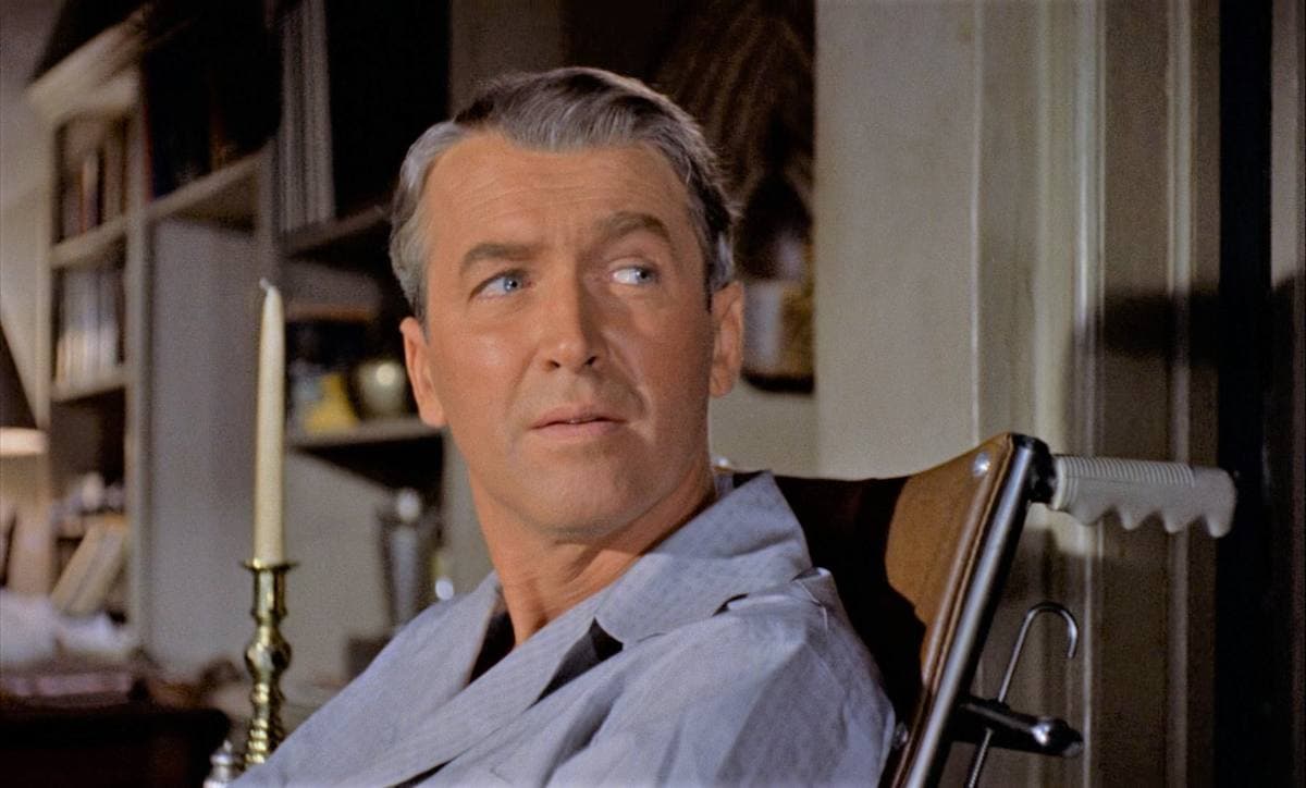 James Stewart in pale blue pyjamas, looking sideways from his chair