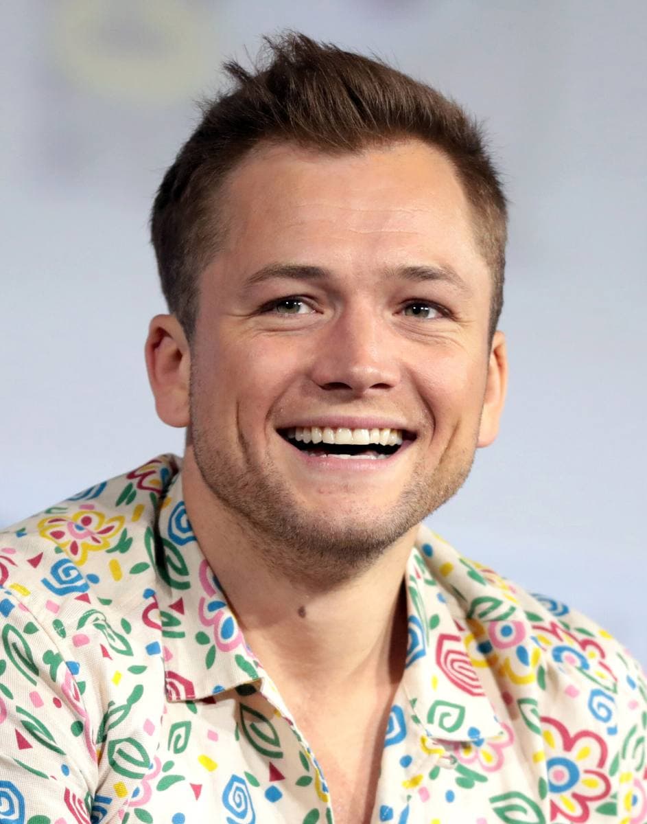 Taron Egerton laughing, in a patterned shirt