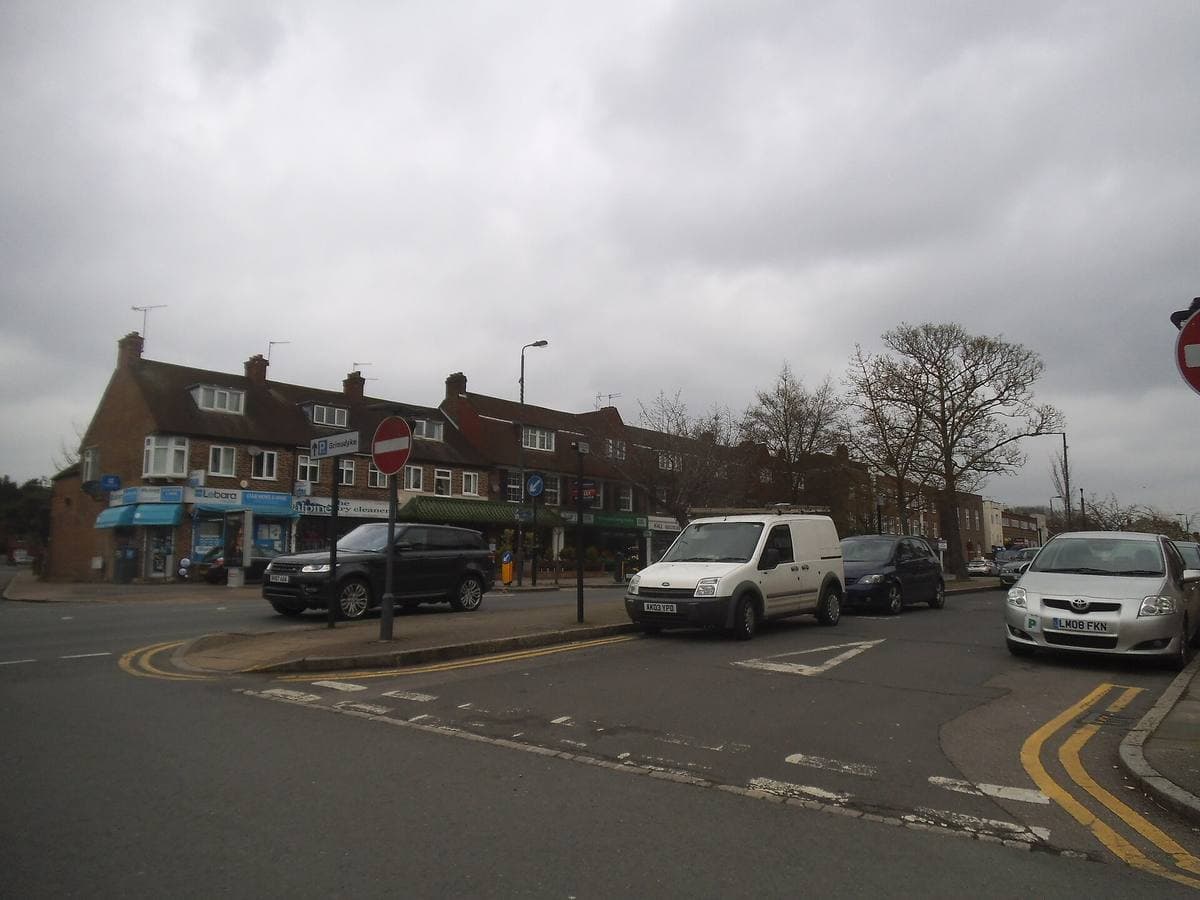 A suburban main road with shops and trees