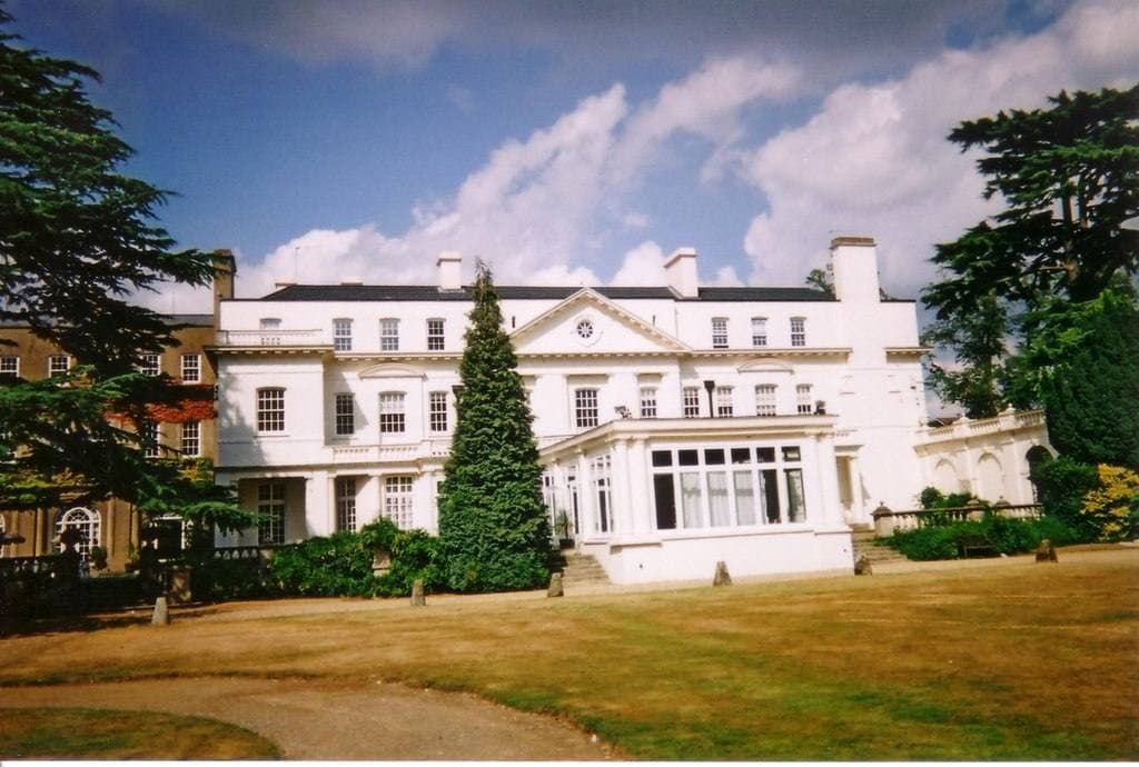 A white country house with a balustraded terrace and lawn