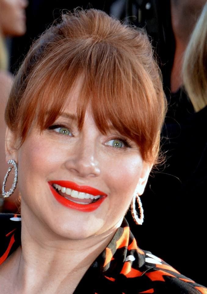 Bryce Dallas Howard smiling, with red hair and red lipstick