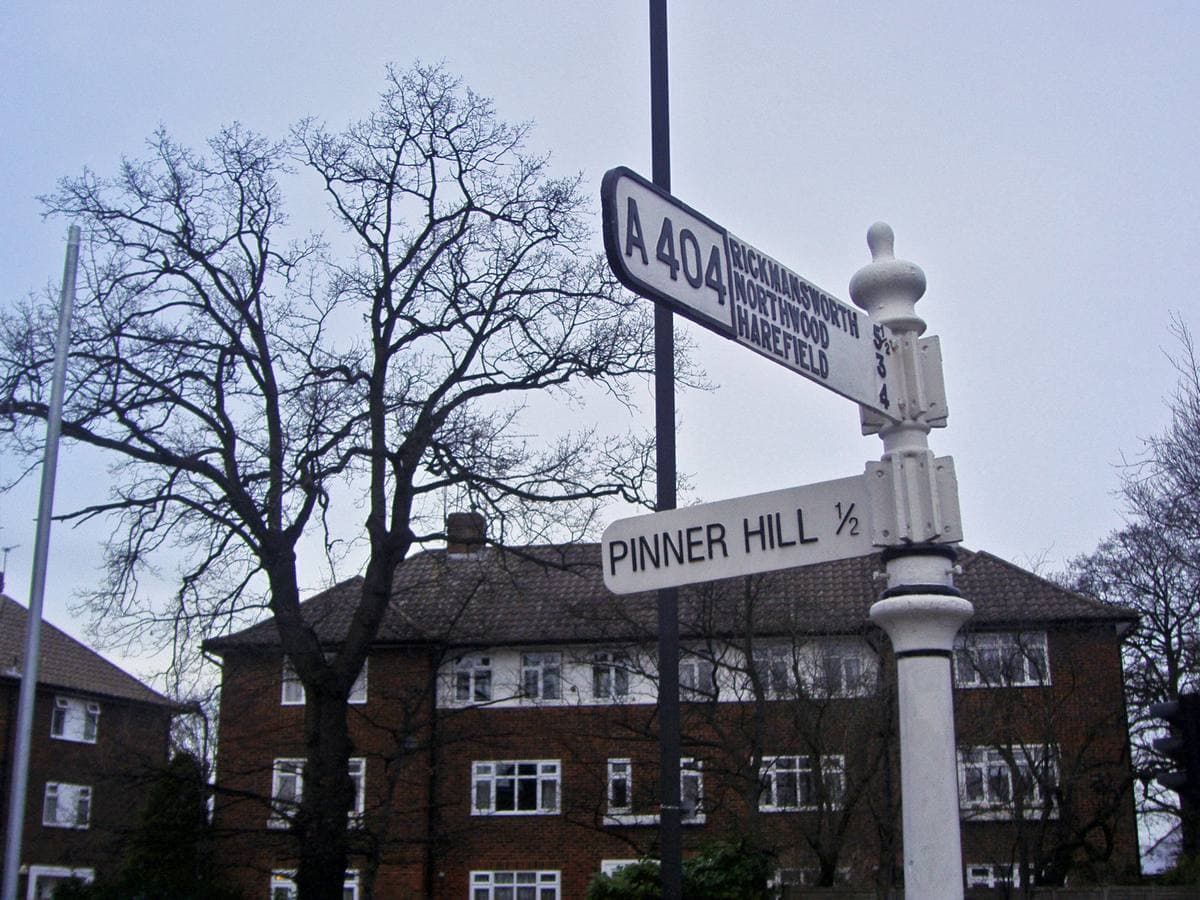 A white fingerpost at a suburban road junction