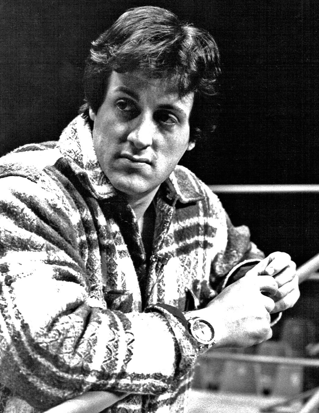 Sylvester Stallone in a patterned cardigan, leaning on the ring ropes and looking at the camera