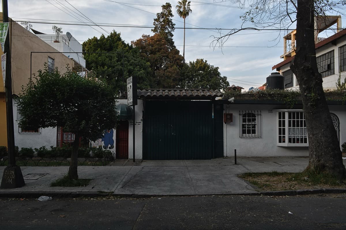 A low house front, a garage door and trees on a Roma Sur street