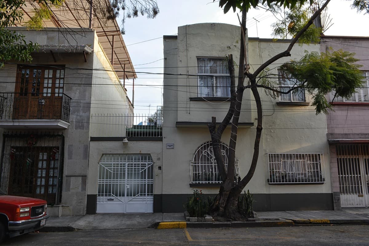 A two-storey house front and a tree on a quiet street