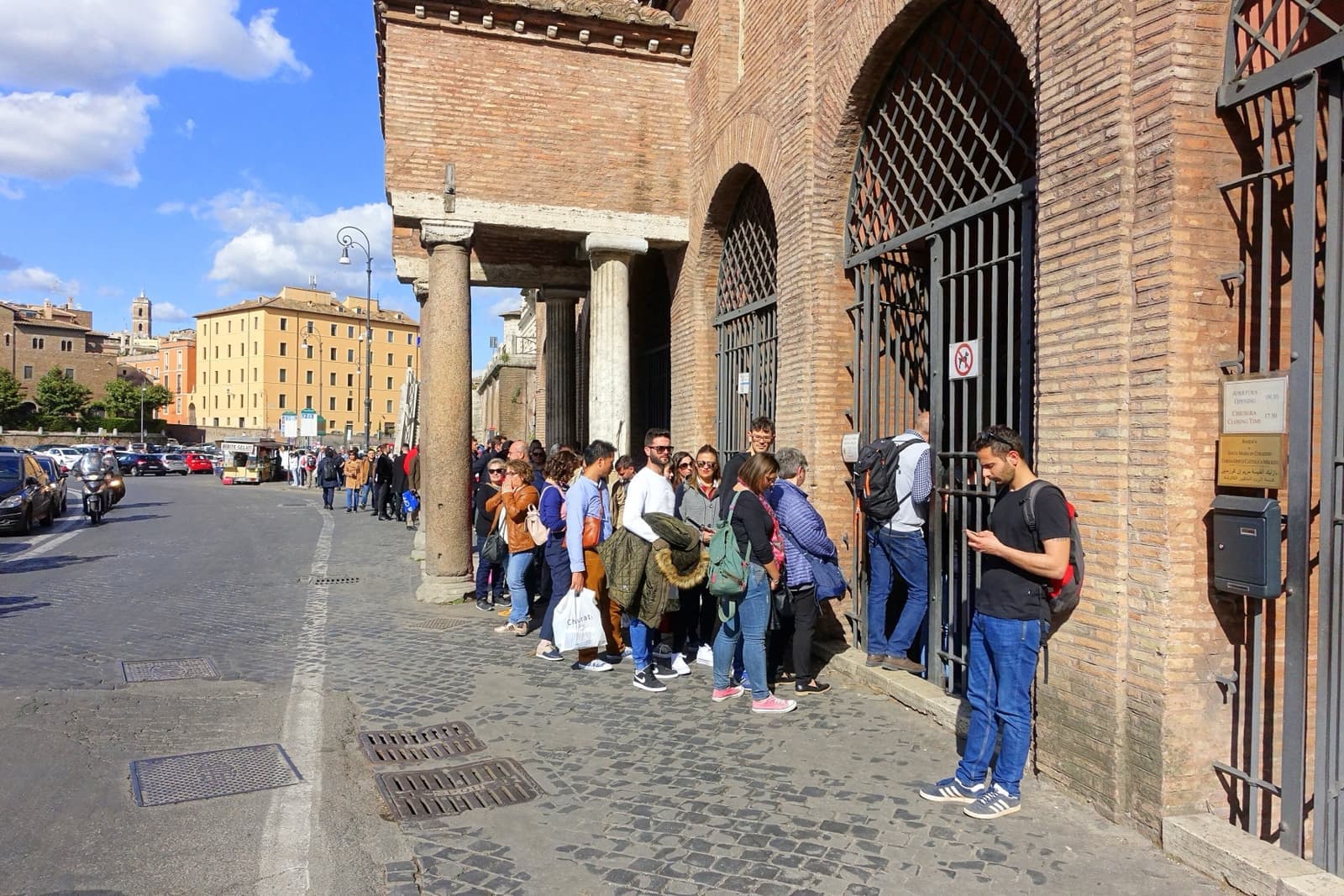 Visitors queuing along the railings of a church portico