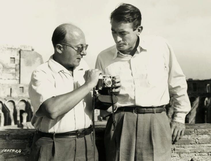 Two men talking beside a film camera on location