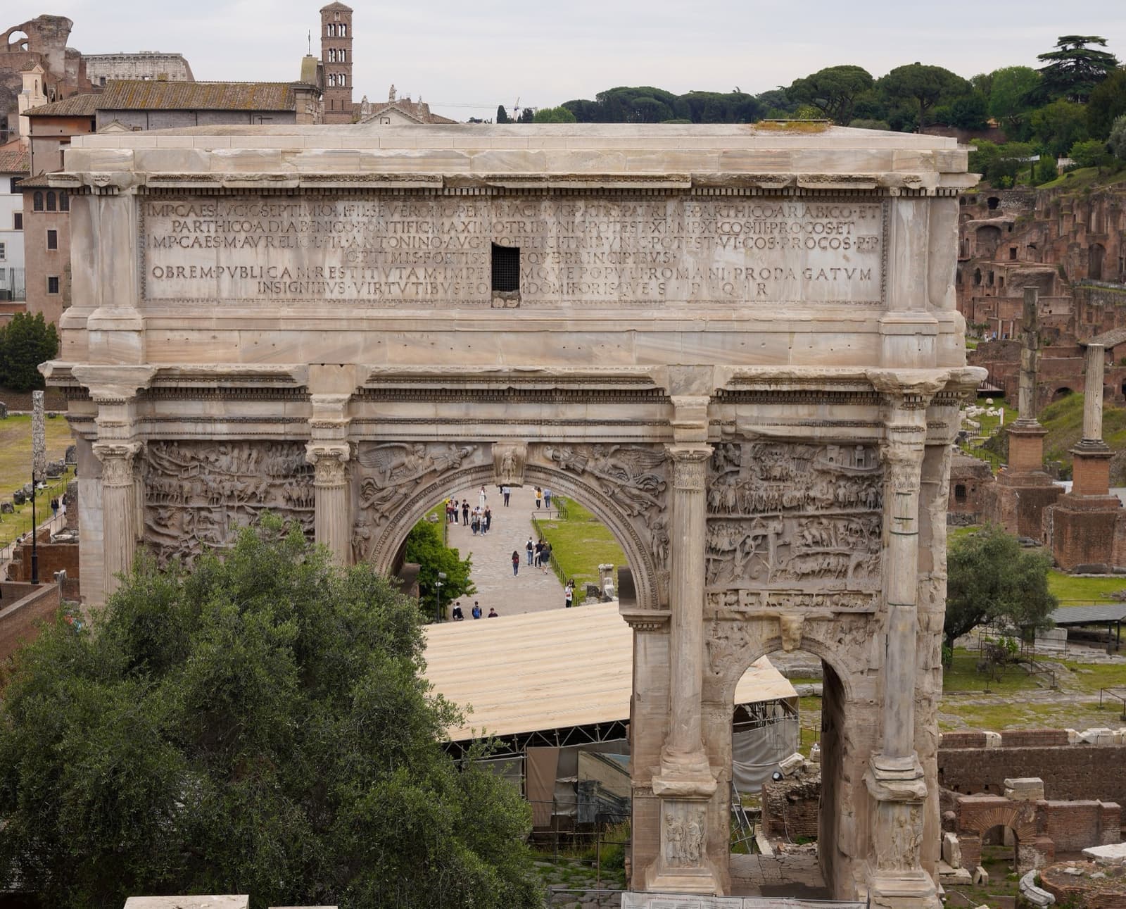A triple marble arch among ruins in the Roman Forum
