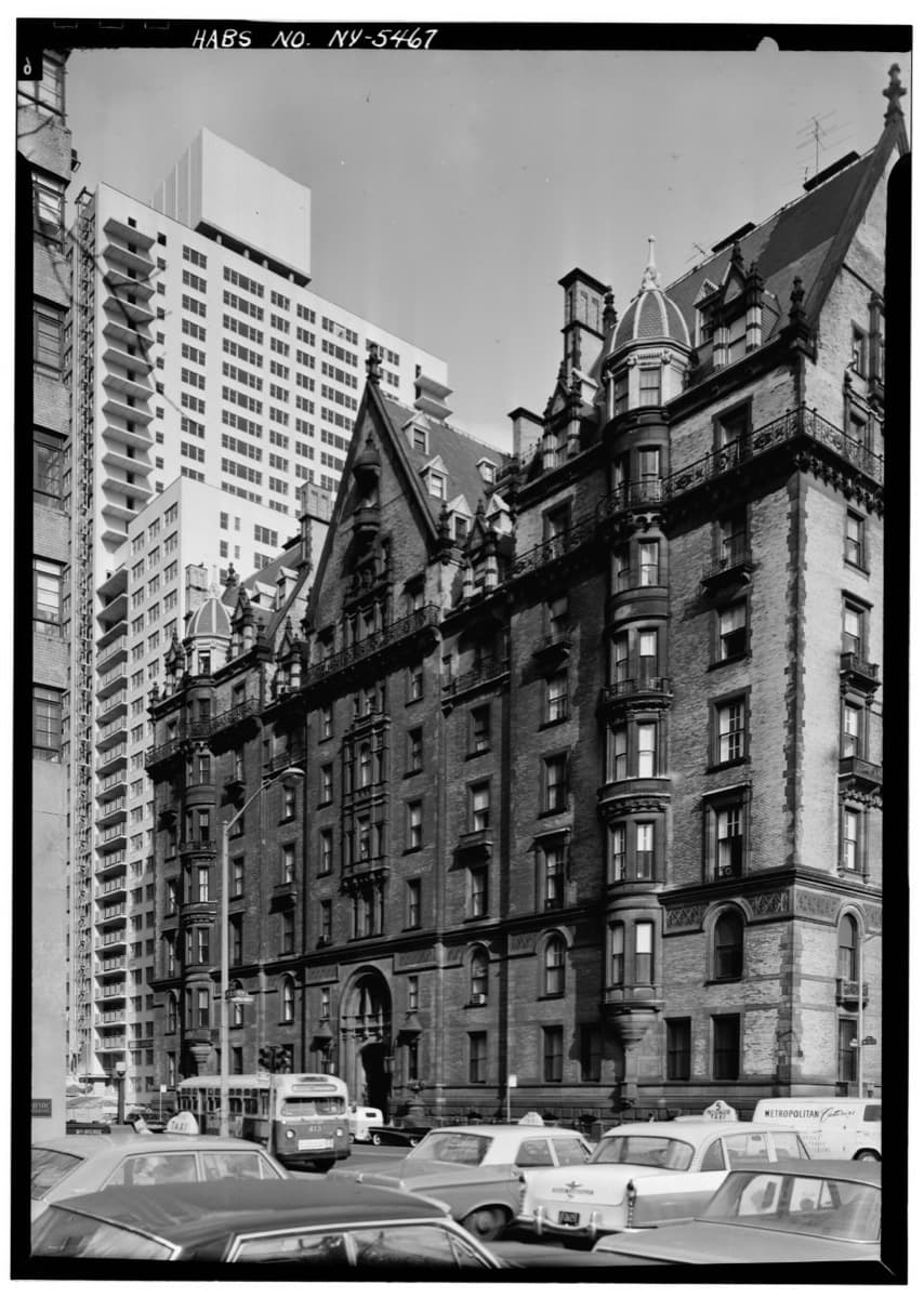 A tall Victorian apartment block with steep roofs and gables seen from the street