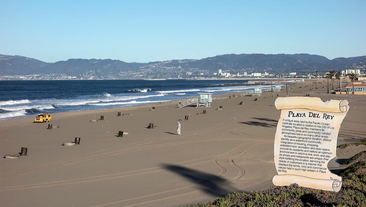 A wide beach and bay with low hills beyond