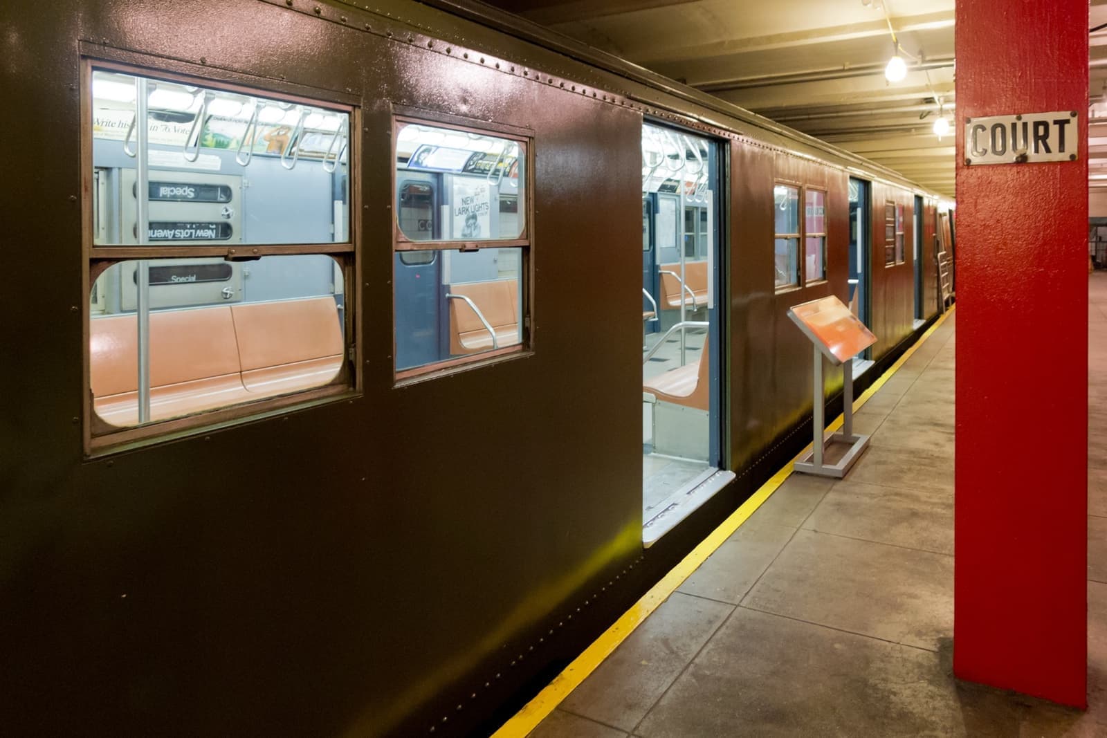 A dark olive vintage subway car numbered 8506 standing at a museum platform with its doors open