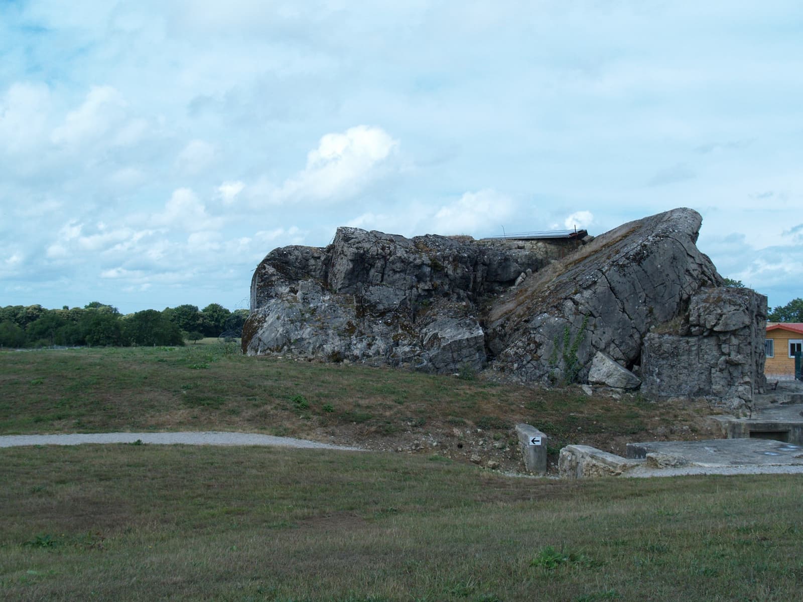 A broken concrete gun casemate on a grassy field